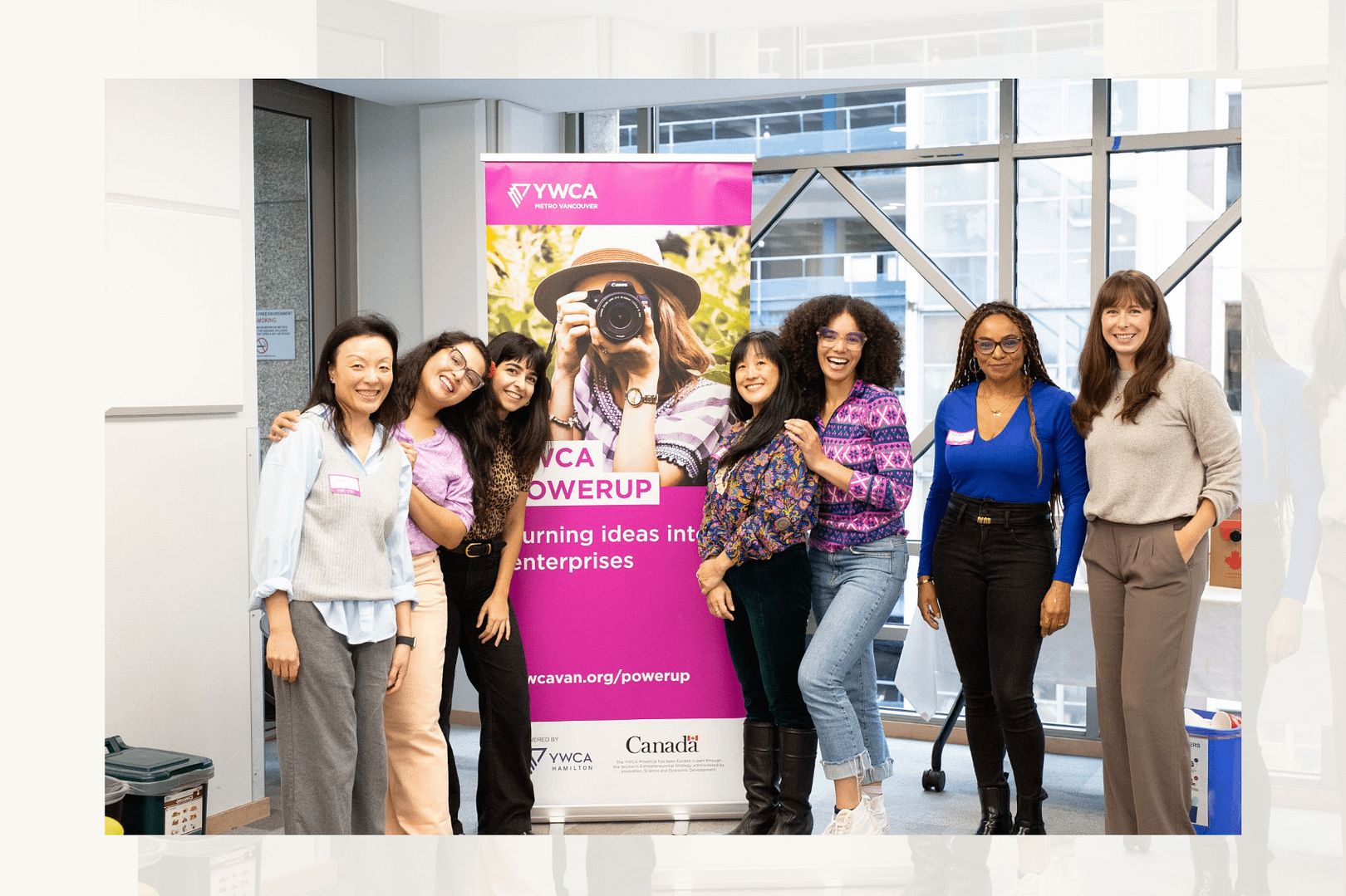a group of women smile towards the camera with a YWCA sign in the background that says it is featuring entrepeneurs